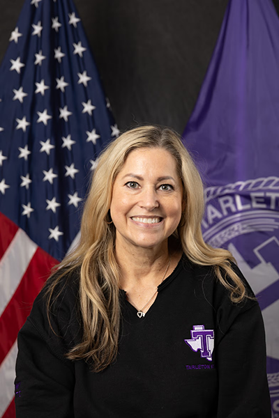 Woman in black Tarleton State sweatshirt poses in front of U.S. and Tarleton State University flags.